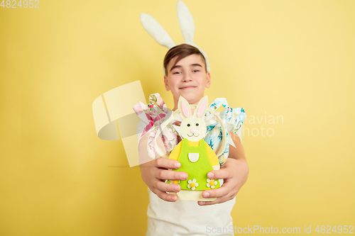 Image of Easter bunny boy with bright emotions on yellow studio background