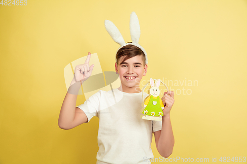 Image of Easter bunny boy with bright emotions on yellow studio background