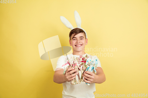 Image of Easter bunny boy with bright emotions on yellow studio background