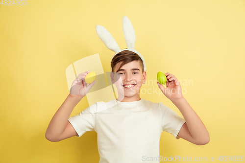 Image of Easter bunny boy with bright emotions on yellow studio background