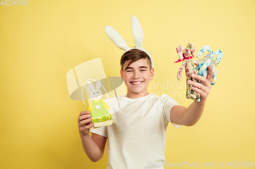 Image of Easter bunny boy with bright emotions on yellow studio background