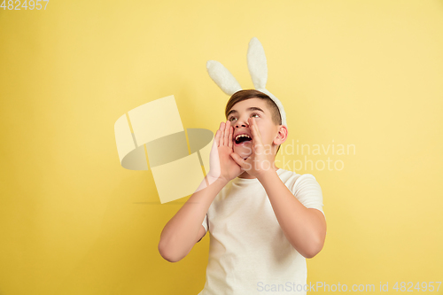 Image of Easter bunny boy with bright emotions on yellow studio background