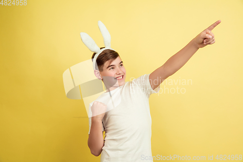 Image of Easter bunny boy with bright emotions on yellow studio background