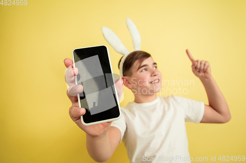 Image of Easter bunny boy with bright emotions on yellow studio background