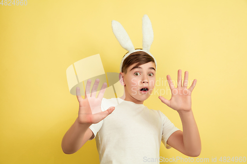 Image of Easter bunny boy with bright emotions on yellow studio background