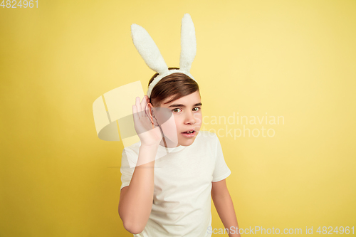 Image of Easter bunny boy with bright emotions on yellow studio background