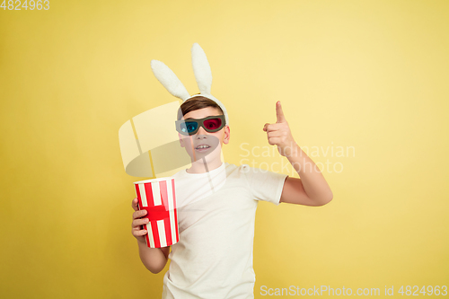 Image of Easter bunny boy with bright emotions on yellow studio background