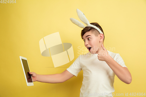 Image of Easter bunny boy with bright emotions on yellow studio background