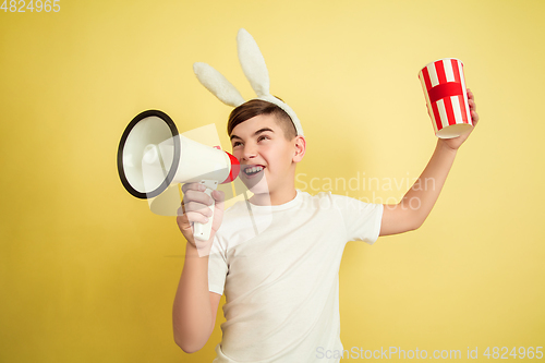 Image of Easter bunny boy with bright emotions on yellow studio background