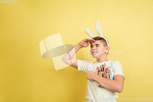 Image of Easter bunny boy with bright emotions on yellow studio background