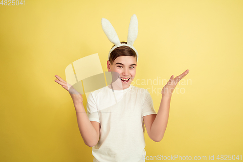 Image of Easter bunny boy with bright emotions on yellow studio background