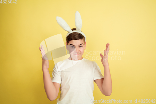 Image of Easter bunny boy with bright emotions on yellow studio background