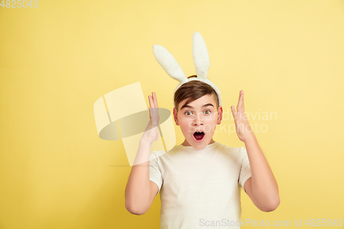 Image of Easter bunny boy with bright emotions on yellow studio background