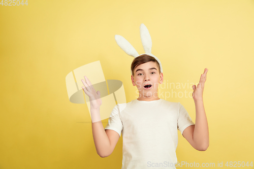 Image of Easter bunny boy with bright emotions on yellow studio background