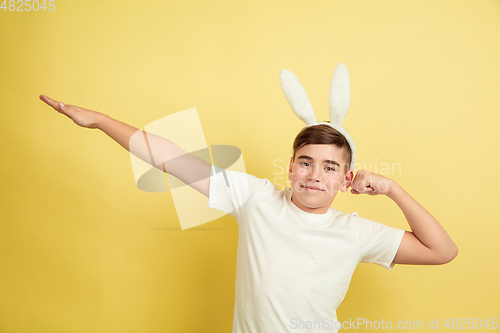 Image of Easter bunny boy with bright emotions on yellow studio background