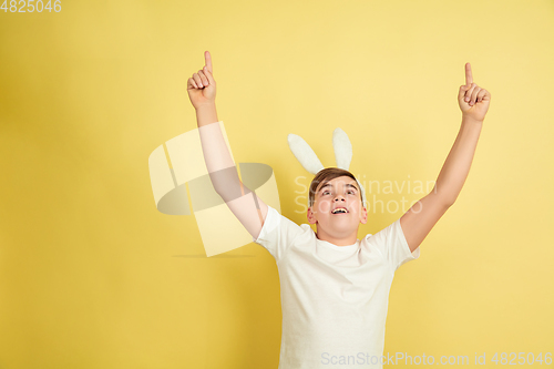 Image of Easter bunny boy with bright emotions on yellow studio background