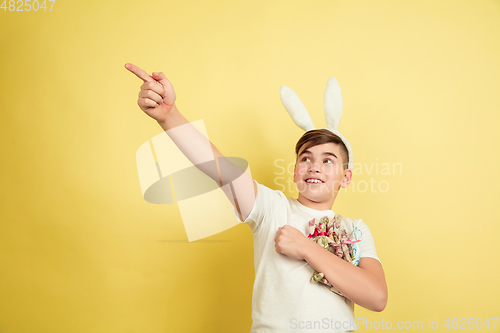 Image of Easter bunny boy with bright emotions on yellow studio background