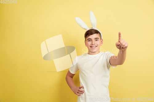 Image of Easter bunny boy with bright emotions on yellow studio background