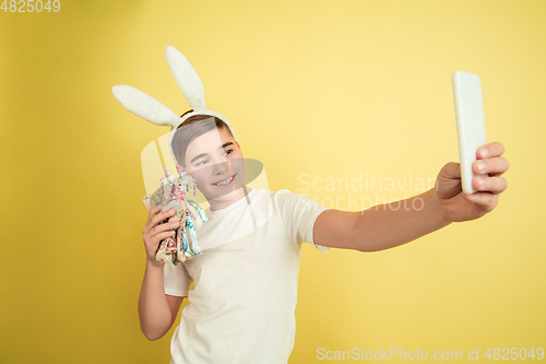 Image of Easter bunny boy with bright emotions on yellow studio background