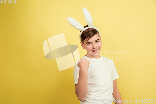 Image of Easter bunny boy with bright emotions on yellow studio background