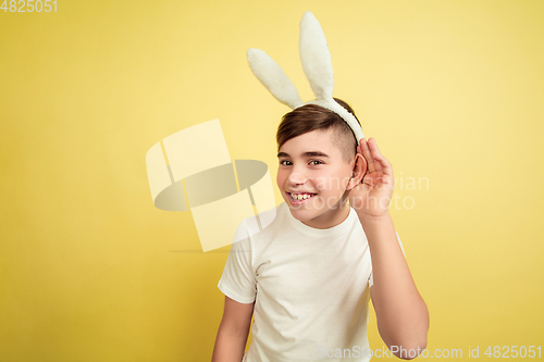 Image of Easter bunny boy with bright emotions on yellow studio background