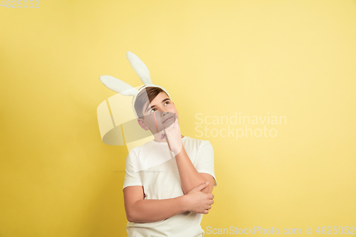 Image of Easter bunny boy with bright emotions on yellow studio background