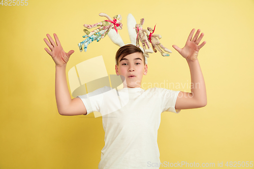 Image of Easter bunny boy with bright emotions on yellow studio background