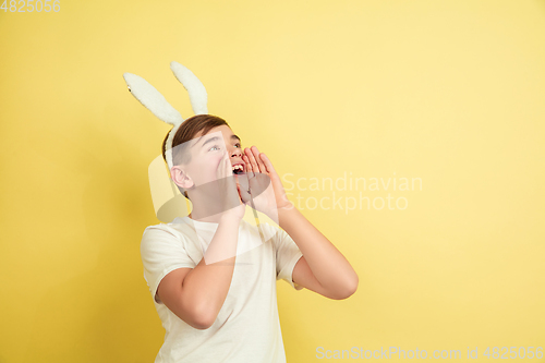 Image of Easter bunny boy with bright emotions on yellow studio background