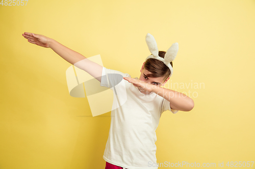 Image of Easter bunny boy with bright emotions on yellow studio background