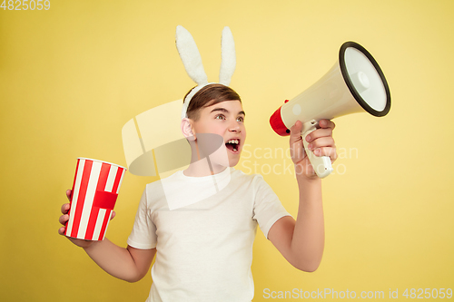 Image of Easter bunny boy with bright emotions on yellow studio background