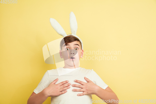 Image of Easter bunny boy with bright emotions on yellow studio background