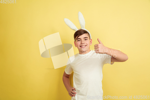 Image of Easter bunny boy with bright emotions on yellow studio background