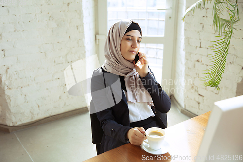 Image of Portrait of a beautiful arabian businesswoman wearing hijab while working