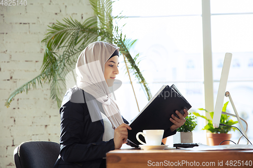 Image of Portrait of a beautiful arabian businesswoman wearing hijab while working