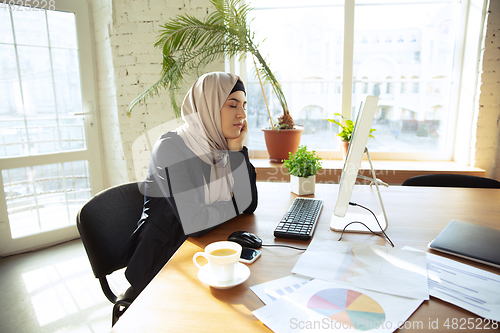 Image of Portrait of a beautiful arabian businesswoman wearing hijab while working
