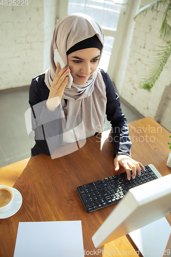 Image of Portrait of a beautiful arabian businesswoman wearing hijab while working
