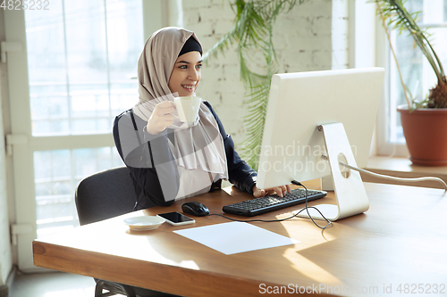 Image of Portrait of a beautiful arabian businesswoman wearing hijab while working
