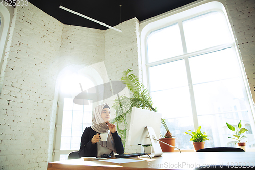 Image of Portrait of a beautiful arabian businesswoman wearing hijab while working