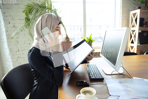 Image of Portrait of a beautiful arabian businesswoman wearing hijab while working