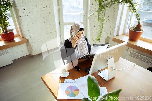Image of Portrait of a beautiful arabian businesswoman wearing hijab while working