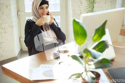 Image of Portrait of a beautiful arabian businesswoman wearing hijab while working