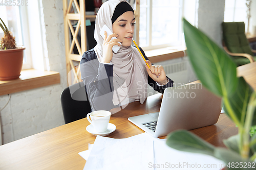 Image of Portrait of a beautiful arabian businesswoman wearing hijab while working