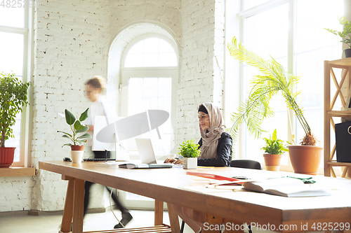 Image of Portrait of a beautiful arabian businesswoman wearing hijab while working