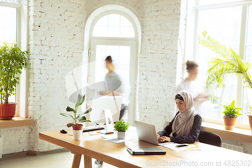 Image of Portrait of a beautiful arabian businesswoman wearing hijab while working