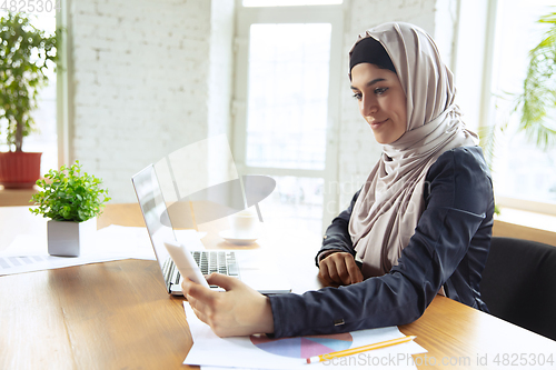Image of Portrait of a beautiful arabian businesswoman wearing hijab while working