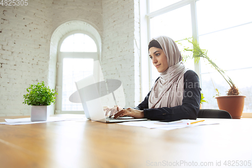 Image of Portrait of a beautiful arabian businesswoman wearing hijab while working