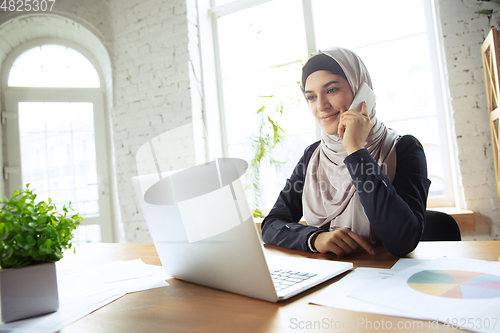 Image of Portrait of a beautiful arabian businesswoman wearing hijab while working