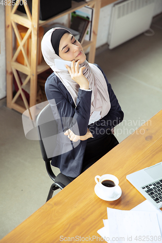 Image of Portrait of a beautiful arabian businesswoman wearing hijab while working