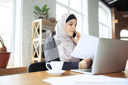 Image of Portrait of a beautiful arabian businesswoman wearing hijab while working