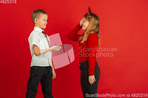 Image of Valentine\'s day celebration, happy caucasian kids isolated on red background